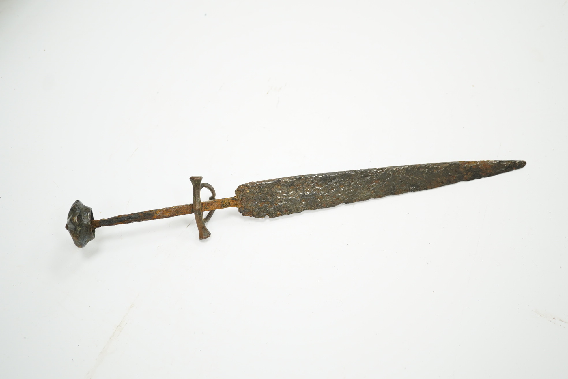A 15th or 16th century dagger in excavated condition, broad tapered single edge blade, bronze crosspiece with side ring and fluted pommel cap, grip now missing. Condition - poor
